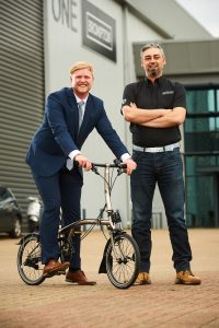 Gareth Ridge, Surface technology Territory Sales Manager (blue suit) and Brompton Design Operations Manager Mo Rahnama with the Surface Technology special edition Nickel Brompton Bike